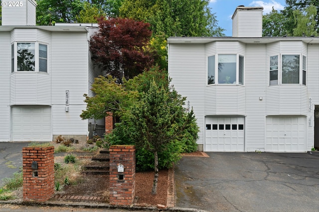 6535 SW Canyon Ct, Portland, OR 97225 - view of front facade with a garage, a chimney, and driveway