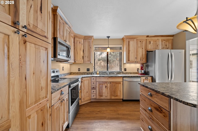 1524 SW 44th St, Pendleton, OR 97801 - kitchen featuring stainless steel appliances, a sink, dark wood-style floors, light brown cabinets, and hanging light fixtures