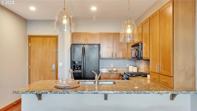 kitchen featuring pendant lighting, sink, a breakfast bar area, black appliances, and kitchen peninsula