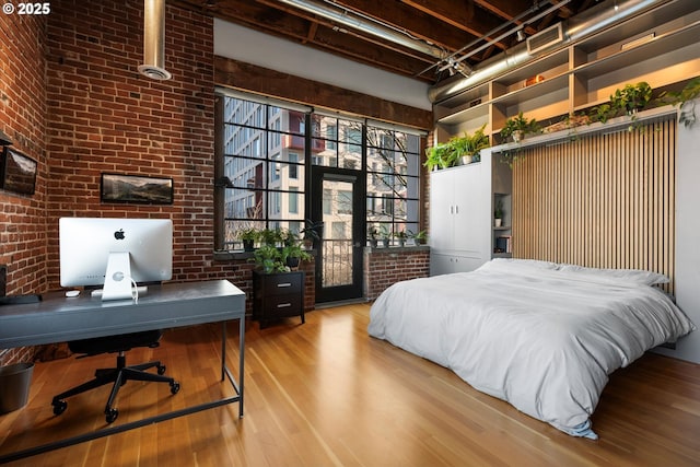 bedroom with brick wall, access to exterior, and light wood-type flooring