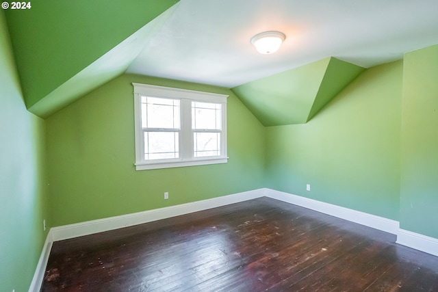 additional living space with baseboards, lofted ceiling, and dark wood finished floors