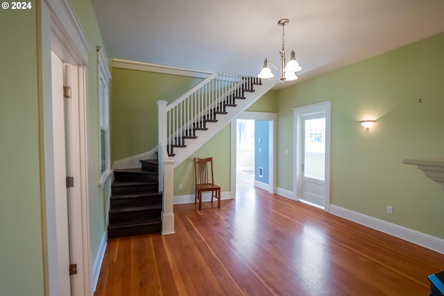 staircase with an inviting chandelier, baseboards, and wood finished floors