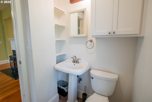 bathroom with toilet, wood finished floors, and baseboards