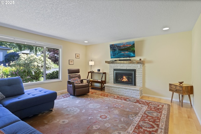 2320 SW Canby Ct, Portland, OR 97219 - living room featuring wood finished floors, a brick fireplace, a textured ceiling, and recessed lighting