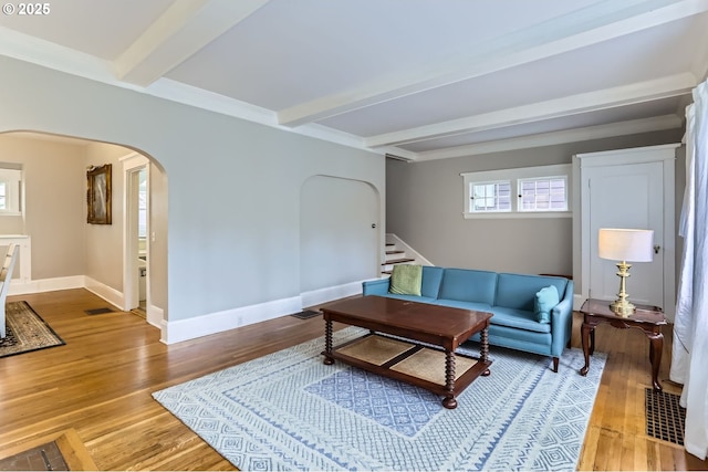 living room with baseboards, beamed ceiling, stairs, wood finished floors, and arched walkways