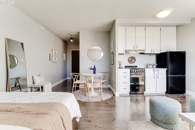 bedroom with black fridge, dark hardwood / wood-style floors, and a textured ceiling