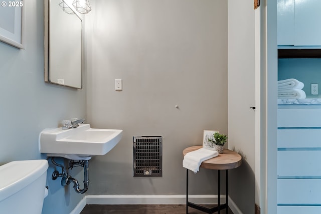 bathroom with wood-type flooring, heating unit, and toilet