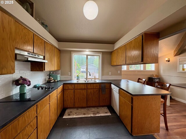 892 S 55th Pl, Springfield, OR 97478 - kitchen featuring under cabinet range hood, a sink, white dishwasher, a peninsula, and black electric stovetop