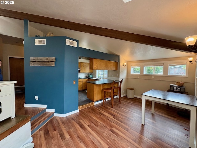892 S 55th Pl, Springfield, OR 97478 - kitchen featuring brown cabinets, a peninsula, wood finished floors, baseboards, and a kitchen bar