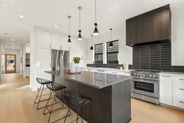 kitchen with decorative backsplash, a breakfast bar area, light wood finished floors, and stainless steel appliances