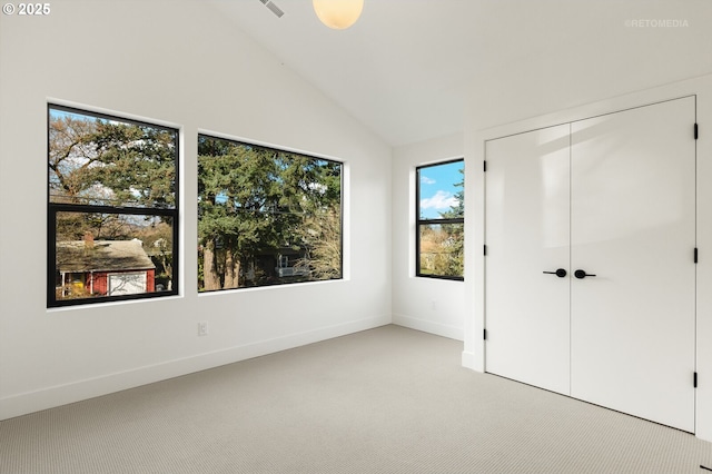 unfurnished bedroom with baseboards, lofted ceiling, light colored carpet, and a closet