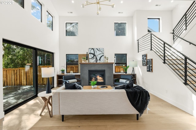 living room with light wood finished floors, visible vents, baseboards, stairs, and a glass covered fireplace