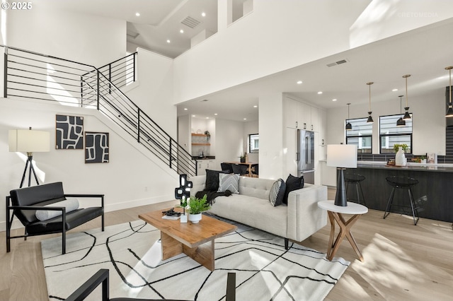 living area featuring visible vents, stairs, recessed lighting, a high ceiling, and light wood-style floors