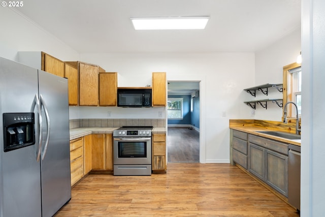 1006 Stillwell Ave, Tillamook, OR 97141 - kitchen featuring appliances with stainless steel finishes, a sink, light wood-type flooring, and baseboards