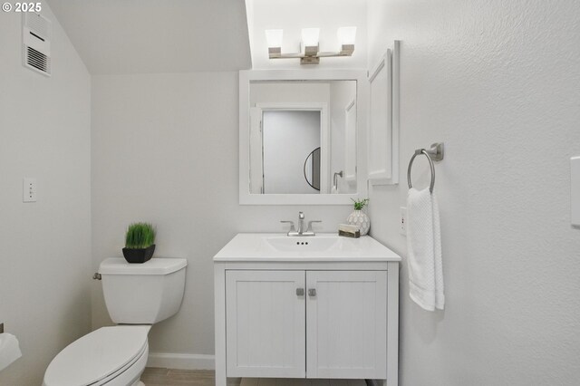 bathroom featuring visible vents, baseboards, toilet, and vanity