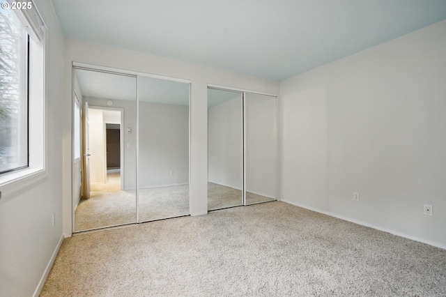 unfurnished bedroom with multiple closets and carpet