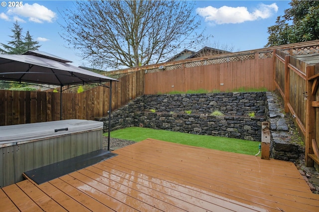 deck with a gazebo, a fenced backyard, and a hot tub