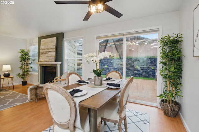 dining space with light wood-type flooring, baseboards, and a fireplace