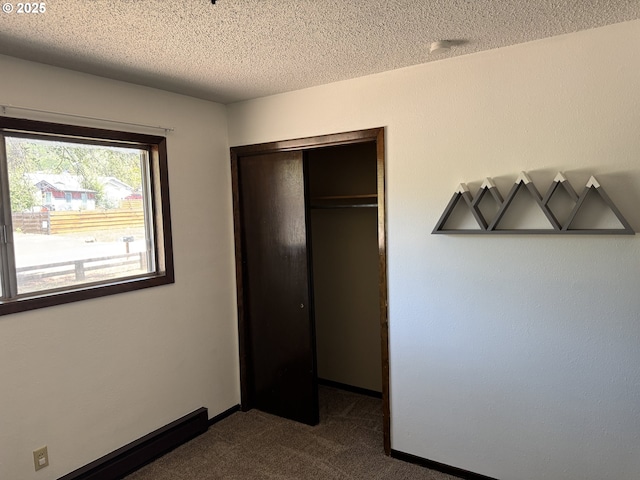 404 NE High St, Goldendale, WA 98620 - unfurnished bedroom with dark carpet, a closet, a textured ceiling, and baseboards