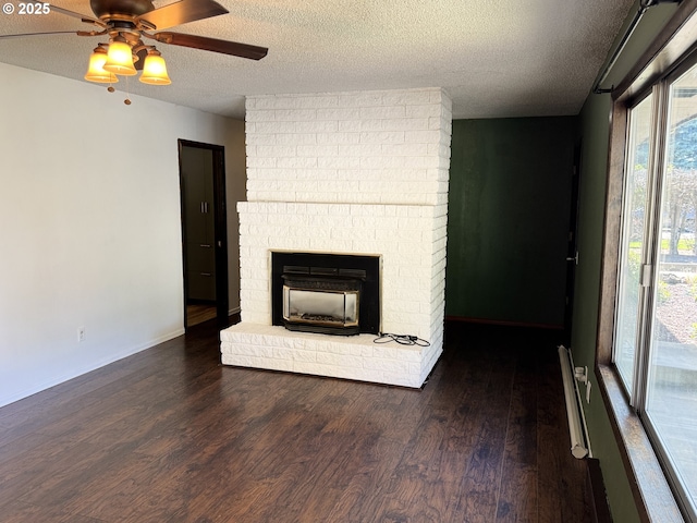 404 NE High St, Goldendale, WA 98620 - unfurnished living room with wood finished floors, a textured ceiling, a ceiling fan, a brick fireplace, and baseboards