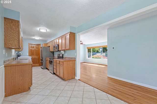 16880 Tracy Ave, Lake Oswego, OR 97035 - kitchen featuring appliances with stainless steel finishes, a textured ceiling, light tile patterned floors, and light countertops