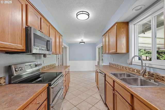 16880 Tracy Ave, Lake Oswego, OR 97035 - kitchen with appliances with stainless steel finishes, a textured ceiling, light tile patterned flooring, brown cabinets, and light countertops