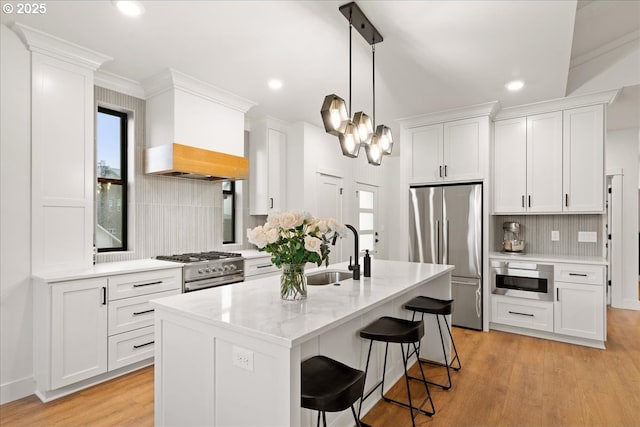 3653 Maidenhair Pl S, Salem, OR 97302 - kitchen featuring a breakfast bar area, light wood-style floors, white cabinetry, decorative backsplash, and appliances with stainless steel finishes