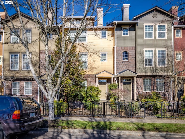 townhome / multi-family property featuring a fenced front yard and brick siding