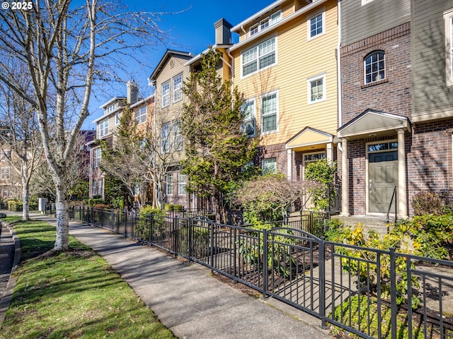 exterior space featuring fence, brick siding, and a residential view