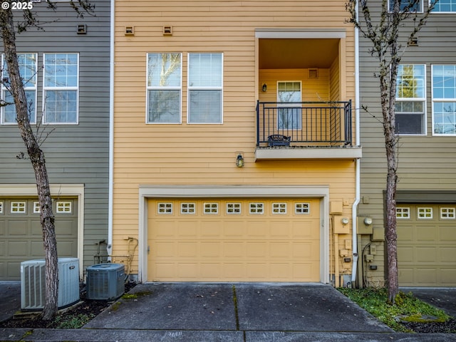 exterior space featuring aphalt driveway, a garage, cooling unit, and a balcony