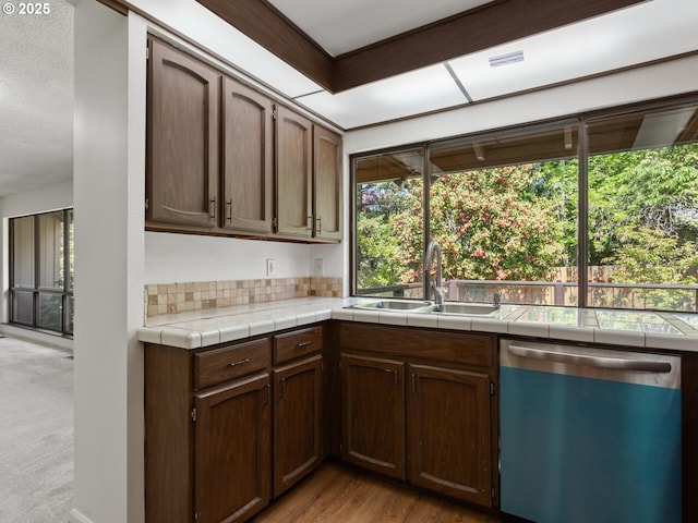 kitchen featuring a sink, tile countertops, dishwasher, and a healthy amount of sunlight