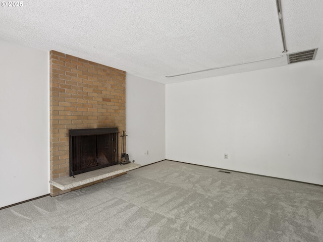 unfurnished living room with carpet floors, a fireplace, a textured ceiling, and visible vents