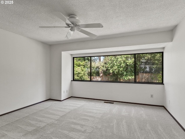 unfurnished room featuring carpet flooring, a textured ceiling, a ceiling fan, baseboards, and visible vents
