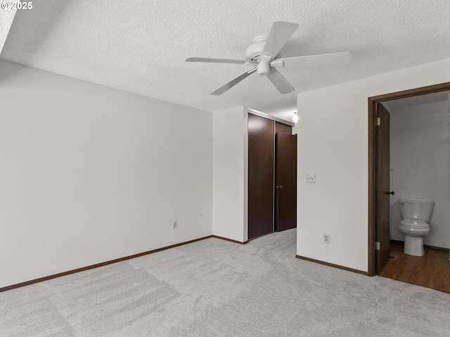 unfurnished bedroom with a textured ceiling, light colored carpet, and baseboards