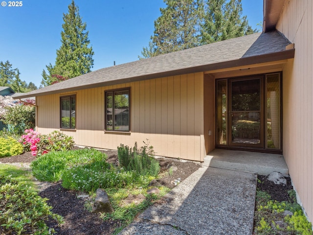 view of exterior entry with roof with shingles