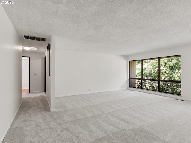 spare room featuring carpet flooring, a textured ceiling, baseboards, and visible vents
