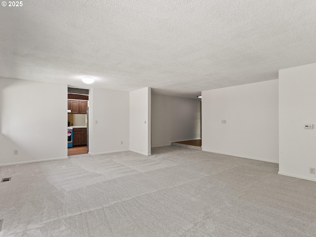 interior space with a textured ceiling, visible vents, light carpet, and baseboards
