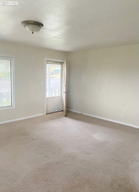 spare room with light colored carpet and baseboards