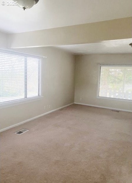 carpeted spare room featuring baseboards and visible vents