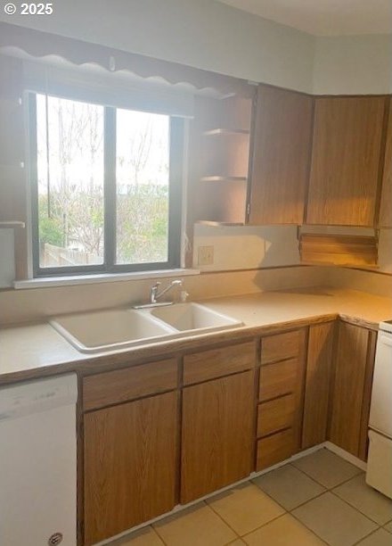 kitchen with open shelves, a sink, white dishwasher, light countertops, and light tile patterned floors