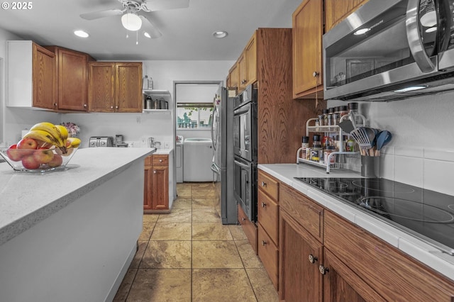 52396 SW 2nd St, Scappoose, OR 97056 - kitchen featuring black appliances, independent washer and dryer, a ceiling fan, brown cabinetry, and recessed lighting