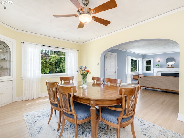 4415 SE Stark St, Portland, OR 97215 - dining space with arched walkways, light wood-style floors, crown molding, ceiling fan, and a fireplace