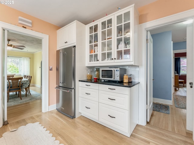 4415 SE Stark St, Portland, OR 97215 - kitchen featuring stainless steel appliances, light wood-type flooring, dark countertops, and glass insert cabinets