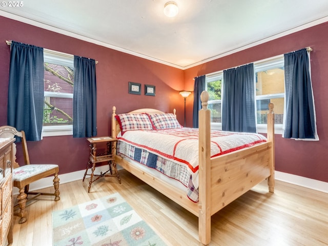 bedroom with wood finished floors, baseboards, and crown molding