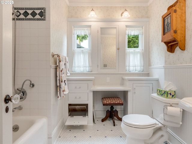 bathroom featuring wallpapered walls, toilet, shower / bath combination, crown molding, and a wainscoted wall