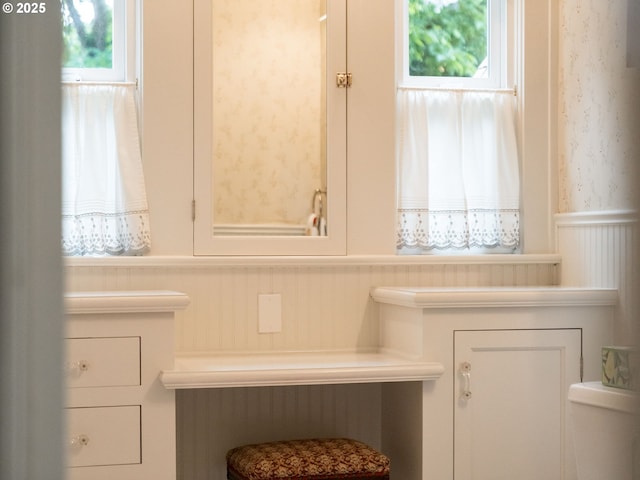 bathroom with a wainscoted wall, a decorative wall, and toilet