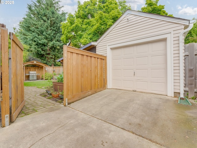 garage featuring concrete driveway and fence