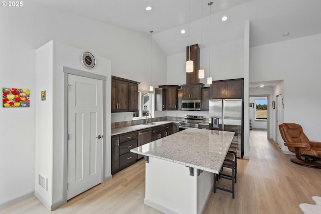 822 Spyglass Dr, Bandon, OR 97411 - kitchen with appliances with stainless steel finishes, high vaulted ceiling, dark brown cabinets, light wood finished floors, and a kitchen island