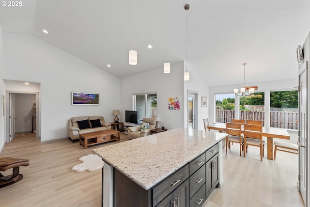 822 Spyglass Dr, Bandon, OR 97411 - kitchen with light wood-style flooring, a chandelier, light stone counters, high vaulted ceiling, and a center island