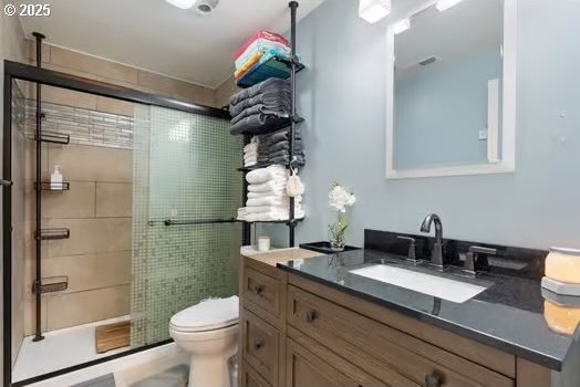 bathroom featuring vanity, toilet, and walk in shower